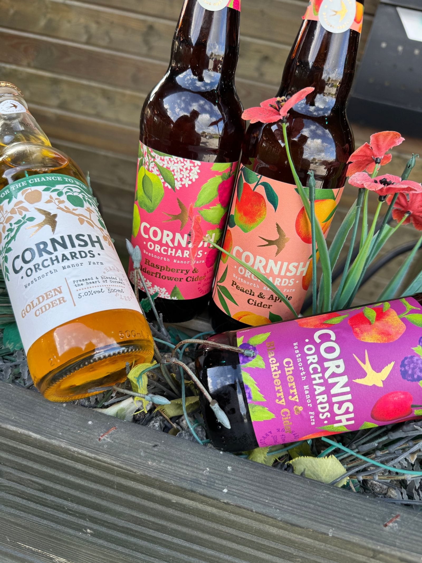 Bottles of local Cornish Orchards cider among the flowers at The Bank at Bude