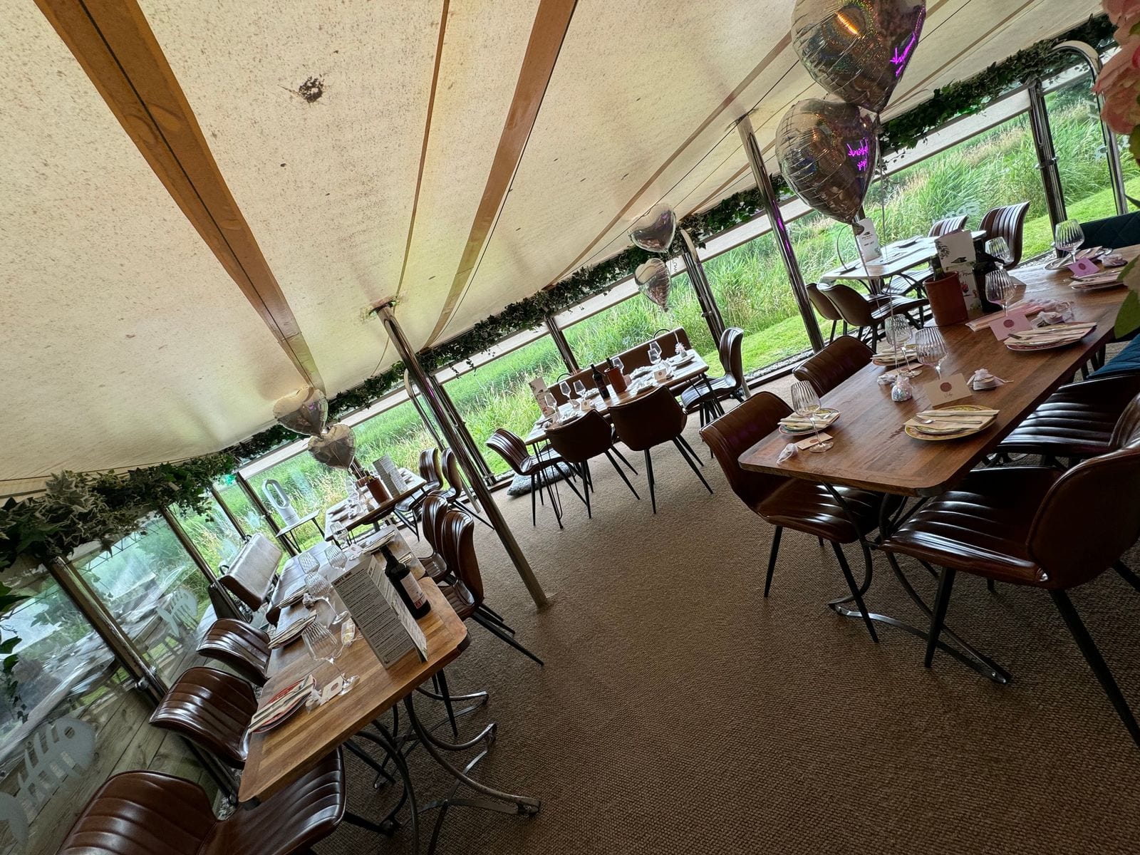 The light-filled marquee dining space at The Bank at Bude set with long tables and balloons for a party