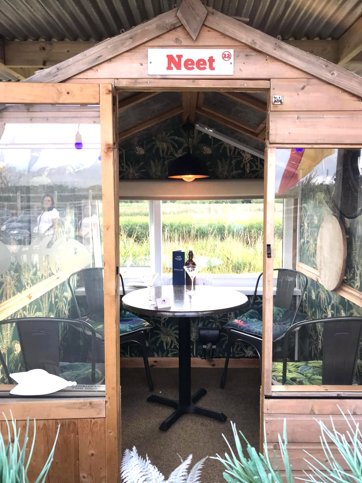 The ‘Neet’ riverside dining pod at The Bank at Bude, with table and chairs and the marshes beyond