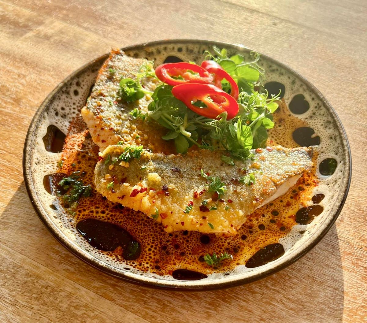 Oven-baked fillet of seabass in chilli and garlic infused olive oil with seasonal greens